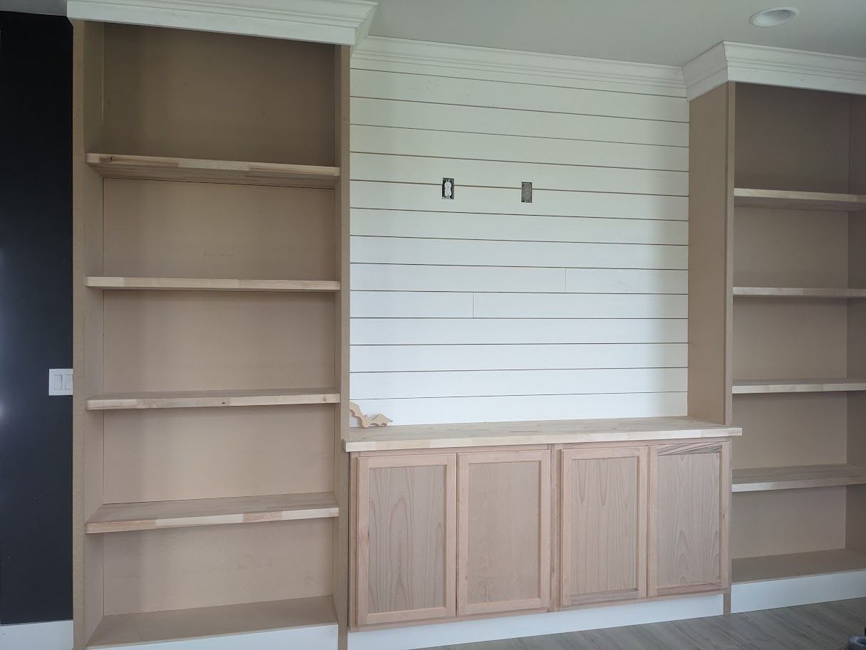 Built-in bookshelves flanking a shiplap TV wall, mid-installation