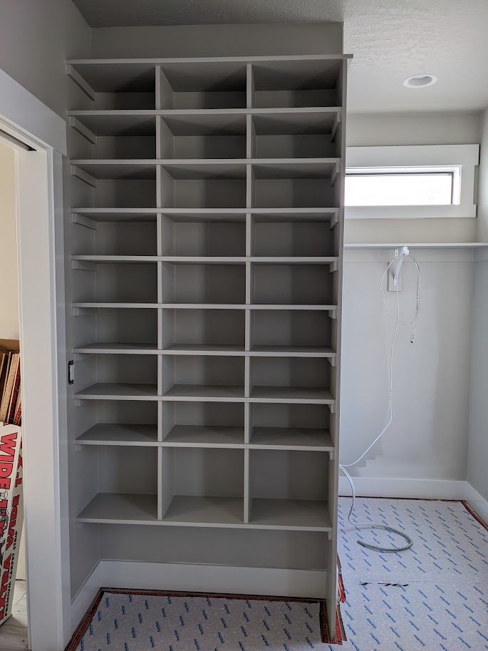 Gray cubby shelving being installed in a closet