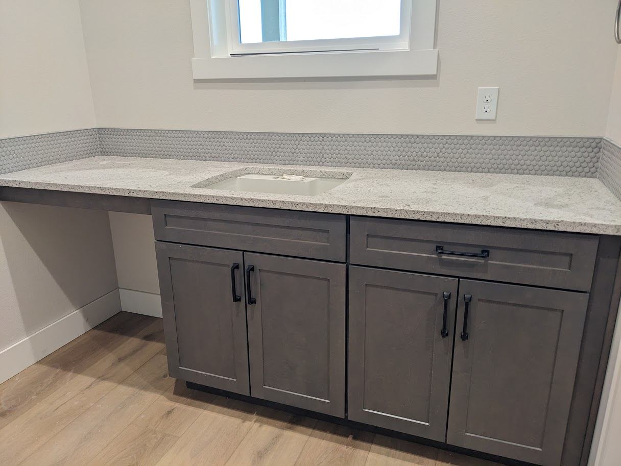 Gray built-in vanity and desk cabinetry under a window