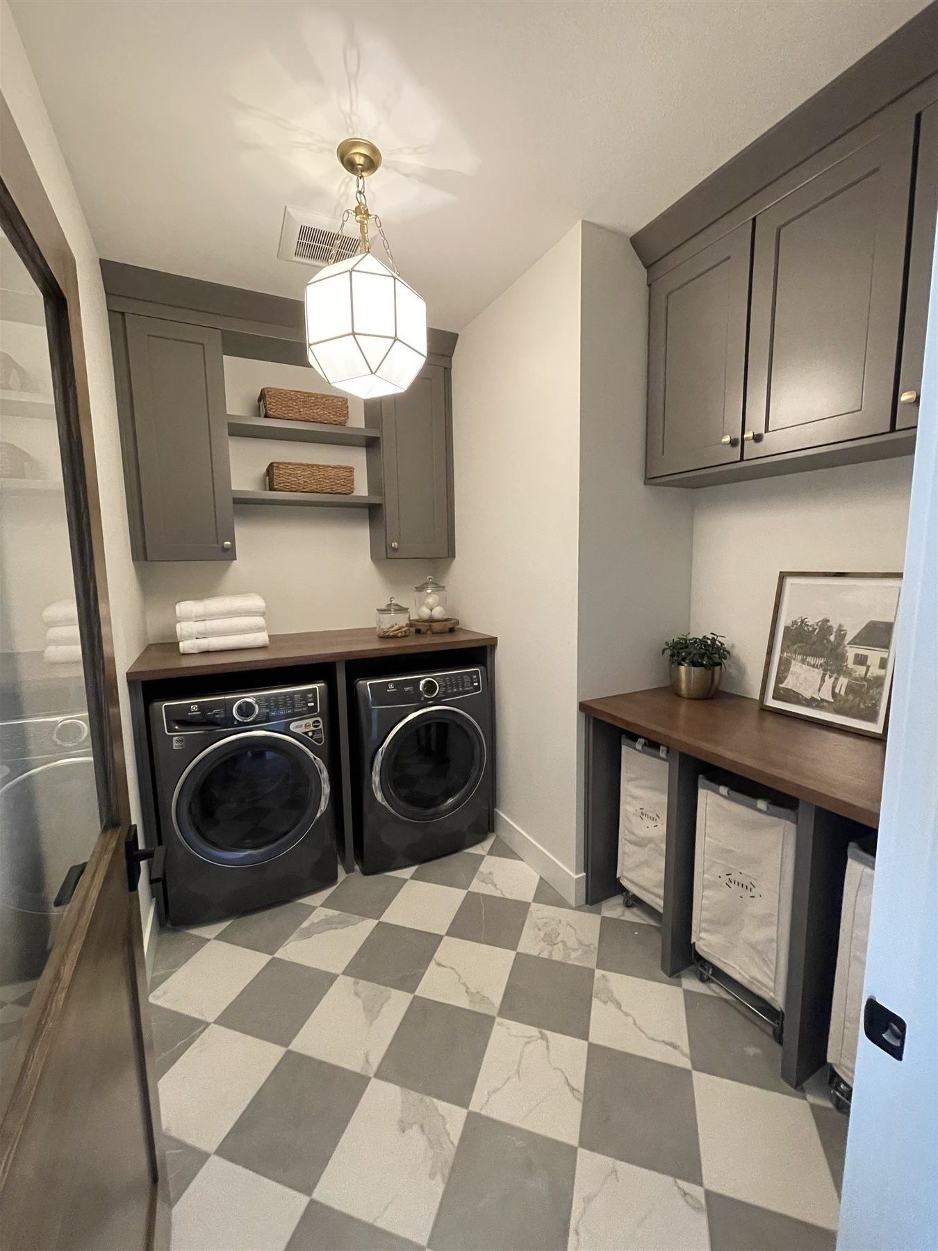 Laundry room with checkered tile floor and two-tone cabinetry