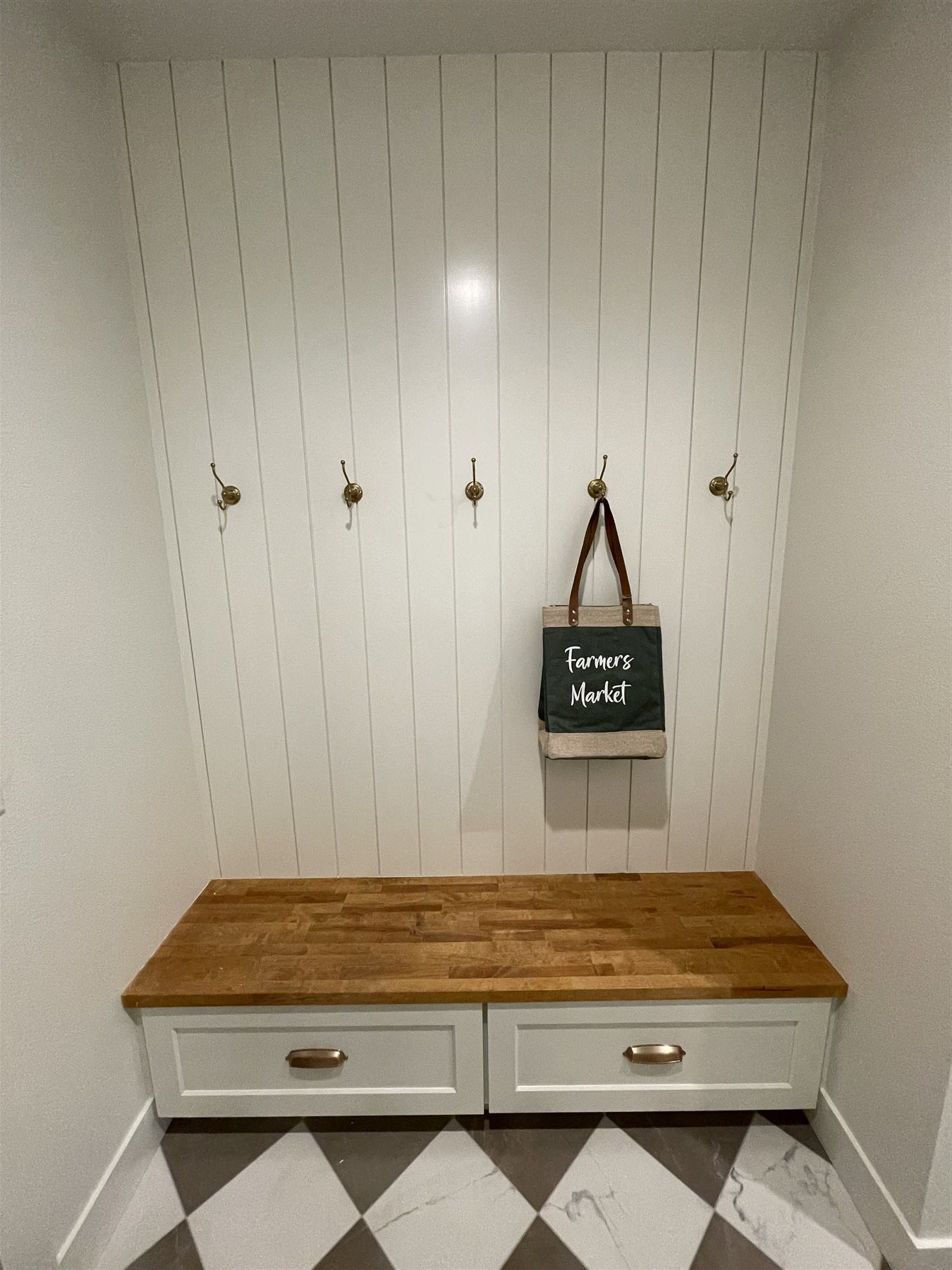 Mudroom nook with shiplap wall, brass hooks, and a butcherblock bench