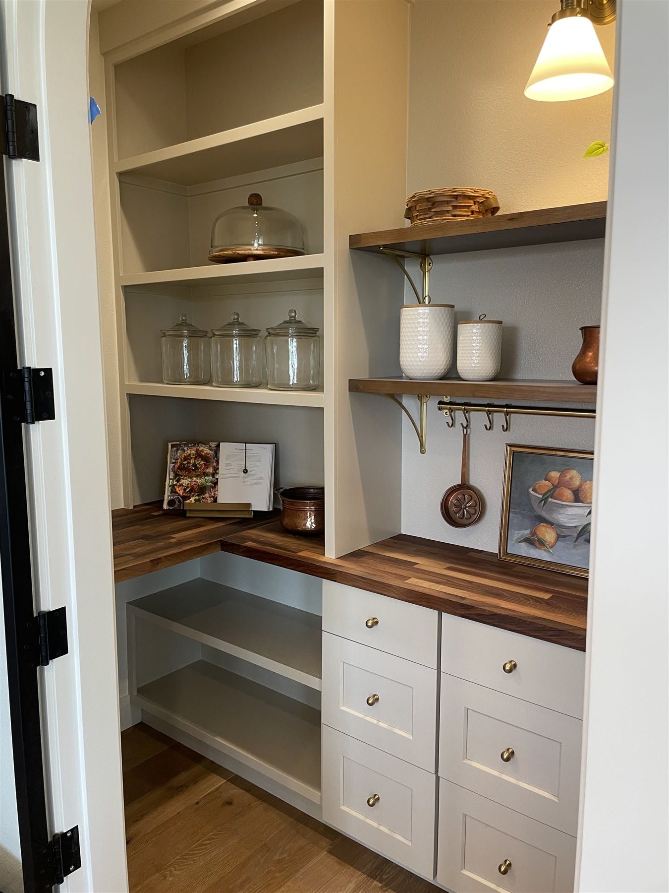 Built-in pantry shelving styled with glass jars, cookbooks, and copper accents