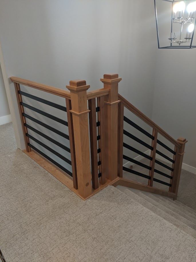 Stair landing with wood newel posts and black metal accent rails