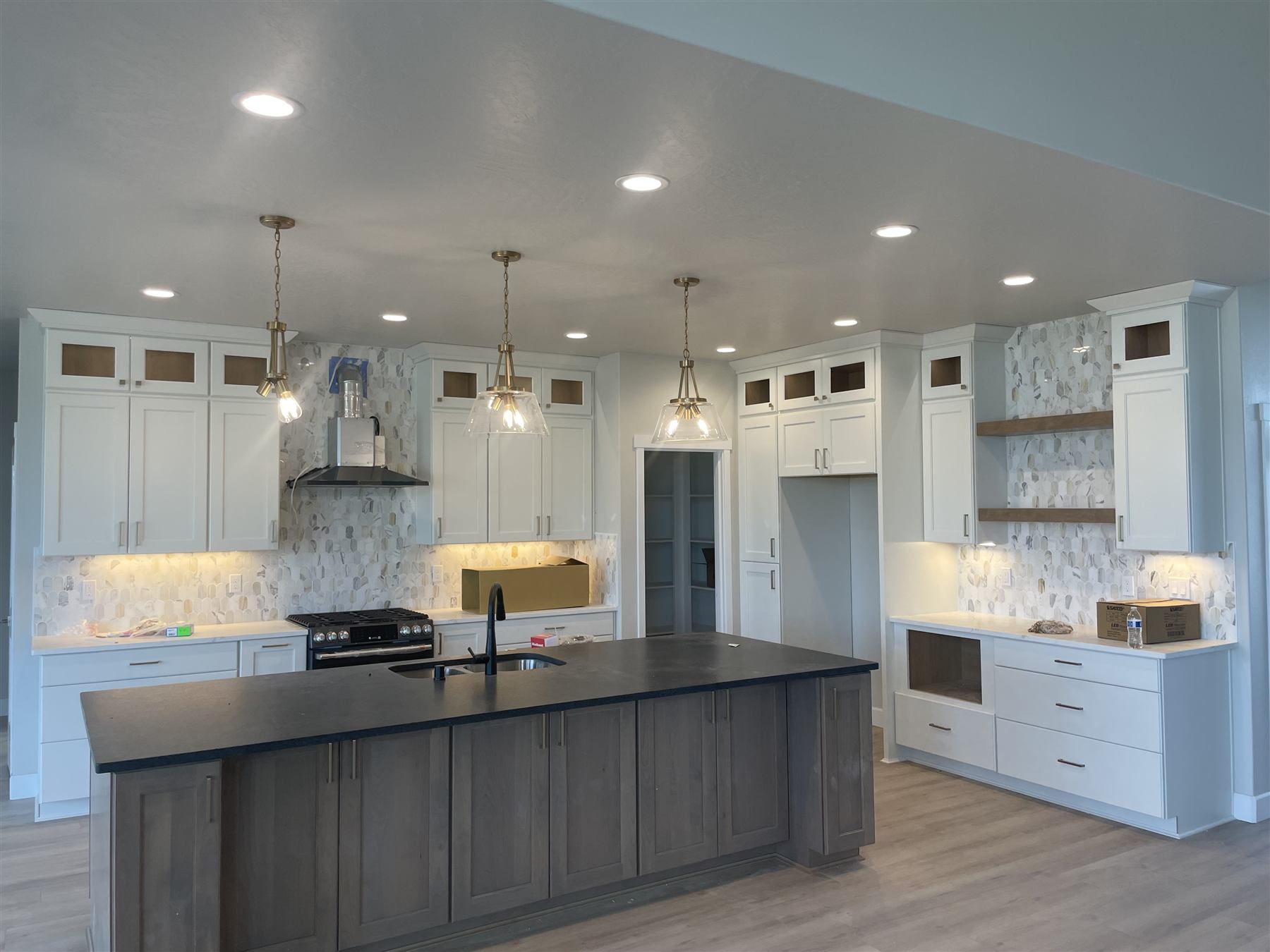White kitchen with brass pendant lights over a dark-stained island