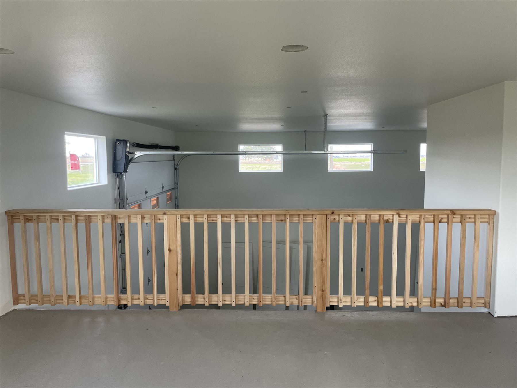 Wood slat railing in an unfinished garage loft space