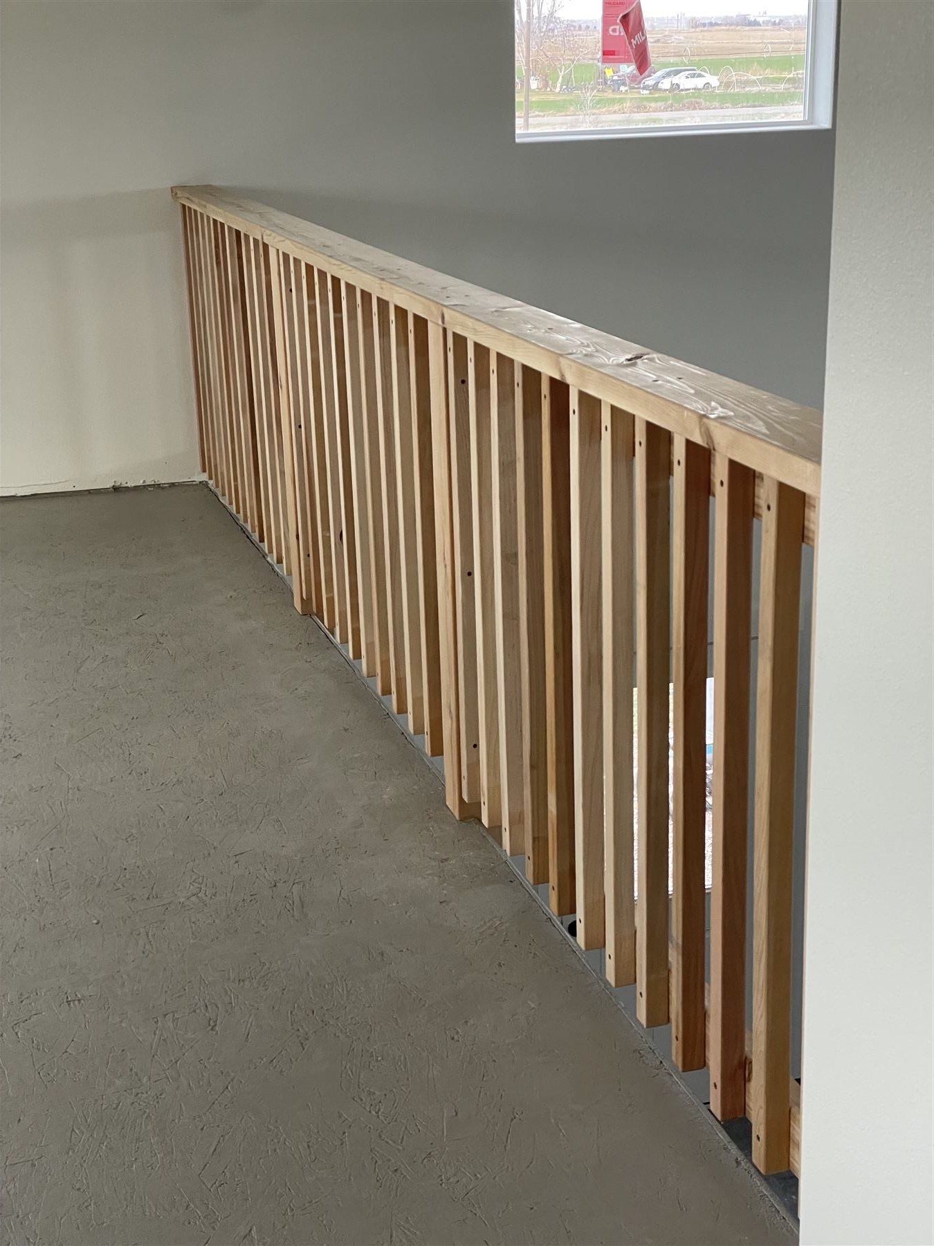 Wood slat loft railing over unfinished subfloor