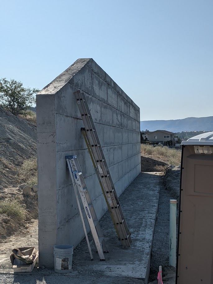 Tall poured concrete foundation wall for a new home, ready for backfill
