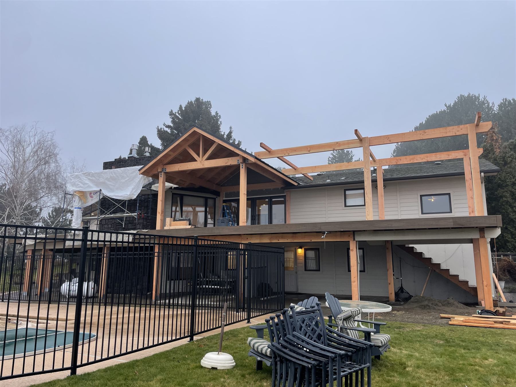 Covered patio and pergola addition under construction near a pool