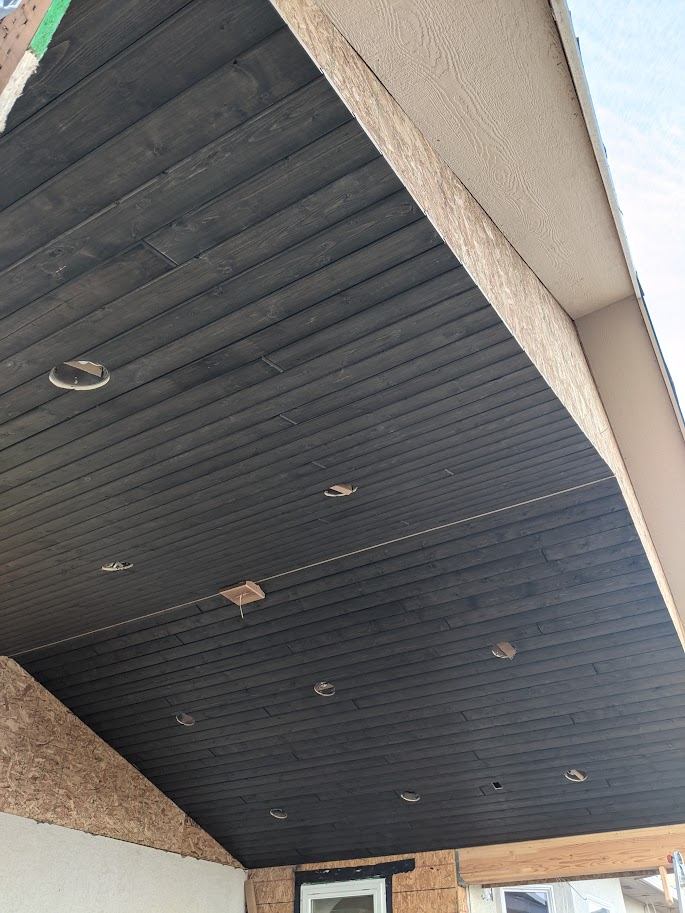 Dark stained tongue-and-groove porch ceiling detail with recessed lighting