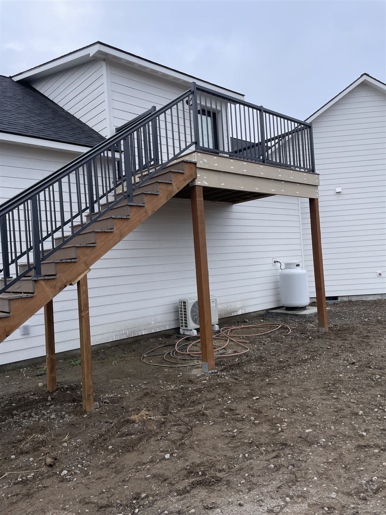 Elevated deck addition with black metal railing and stairs
