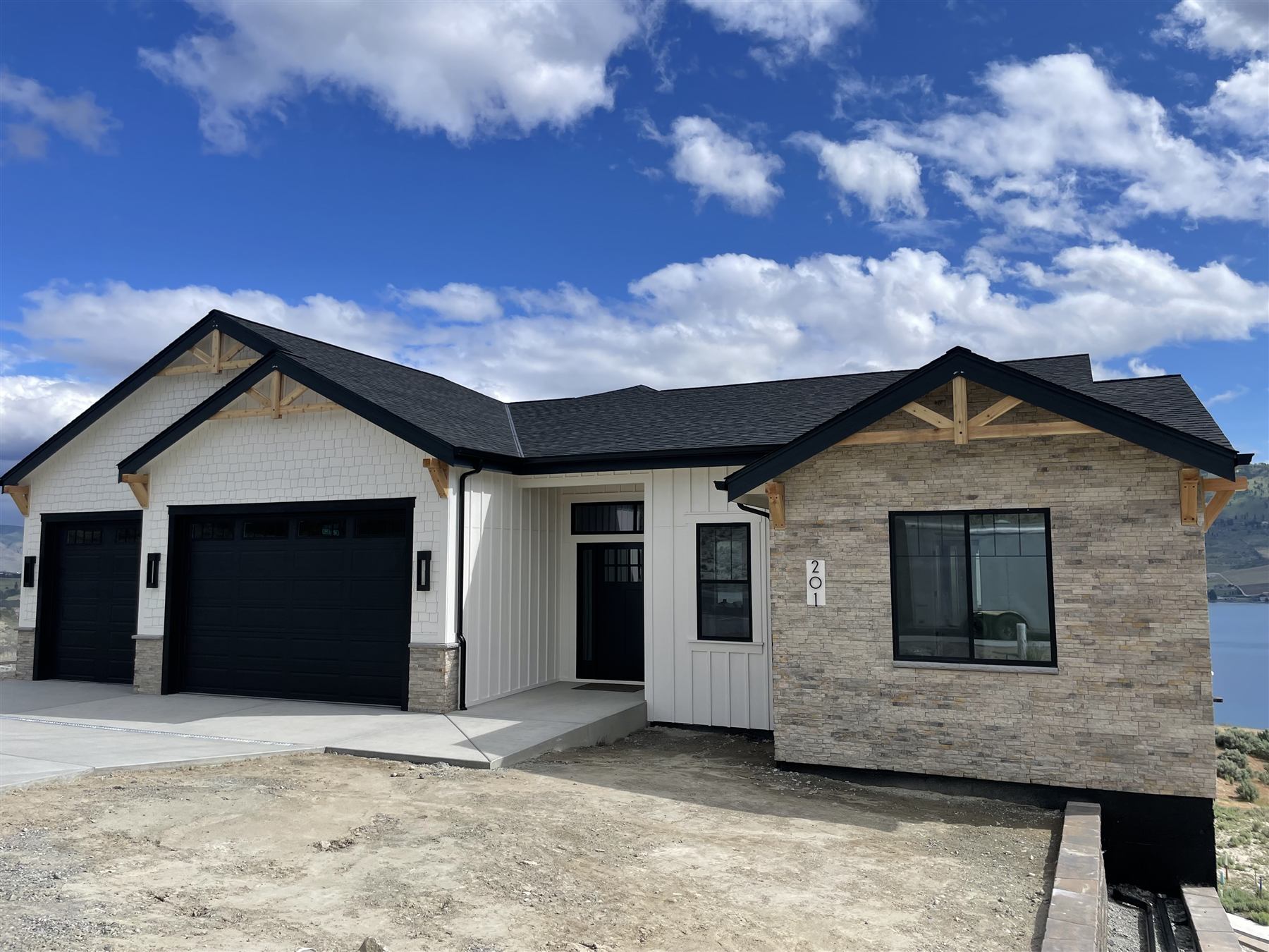 Finished home addition front exterior with stacked-stone accent and black garage doors