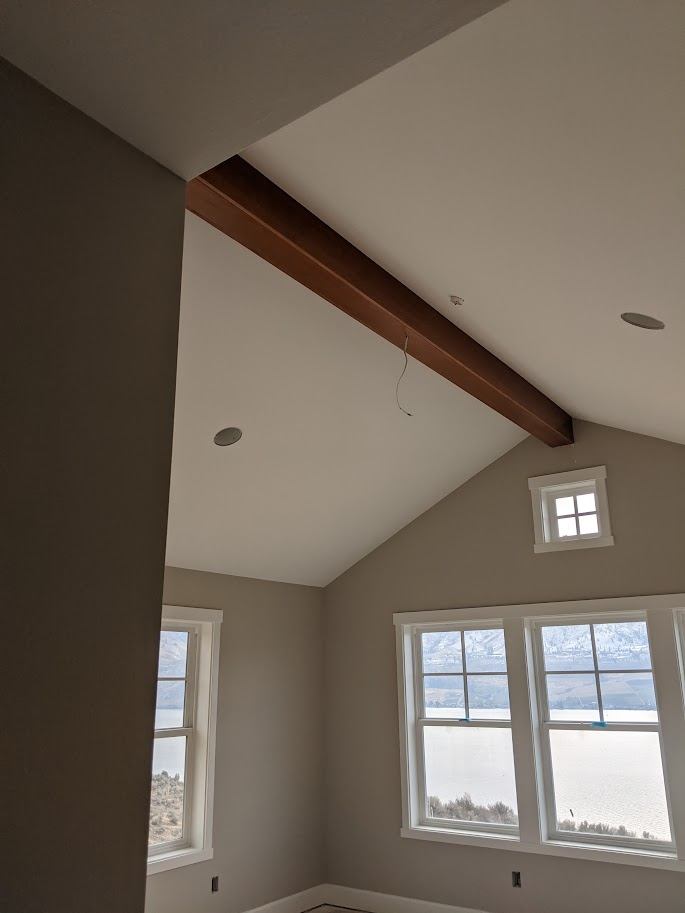 Vaulted ceiling with a stained wood beam and window trim